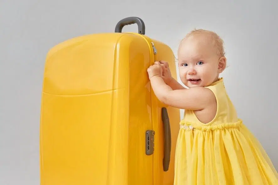 Bebé con una maleta amarilla para el viaje